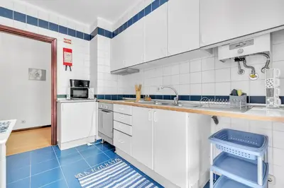 a kitchen with white cabinets and a blue floor at Apartamento São João in Funchal
