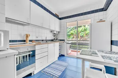 a kitchen with white cabinets and a blue floor at Apartamento São João in Funchal