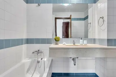 a bathroom with a sink and a tub and a mirror at Apartamento São João in Funchal
