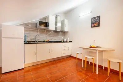 a kitchen with a table and a white refrigerator at Ribeiro´s House, New apartment with amazing sunsets in Arco da Calheta