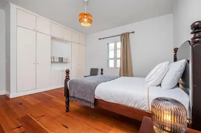 a white bedroom with a bed and a chair at Villa Magnólia in Funchal