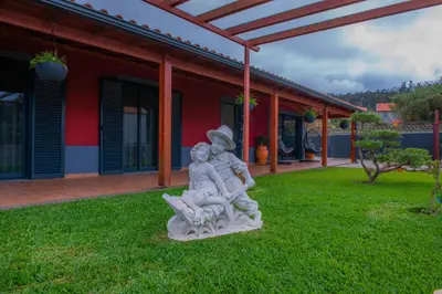 a statue of two people sitting on the grass in front of a house at Villa Rosa in Porto Moniz