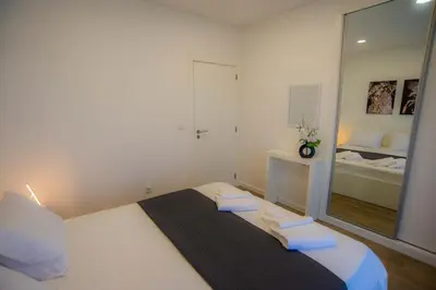 a bedroom with a large white bed with a mirror at Villa Rosa in Porto Moniz