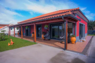 a red house with a deck with plants on it at Villa Rosa in Porto Moniz