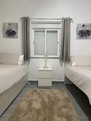 a bedroom with two beds and a window and a rug at Cantinho de Sagres in Sagres