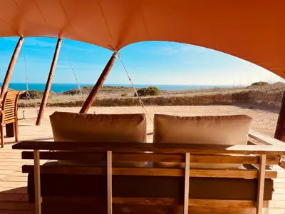 a table with two chairs and an umbrella on the beach at Quinta Aurora in Burgau