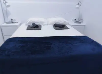 a bed with a blue blanket and two pillows on it at Santo António Guest Apartment in Funchal