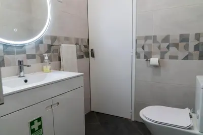 a bathroom with a toilet and a sink and a mirror at City Heart Funchal in Funchal