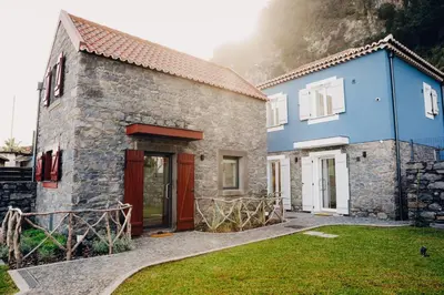 a stone house with a red door and a blue building at Casas do Calhau Miúdo - Seixal in Seixal