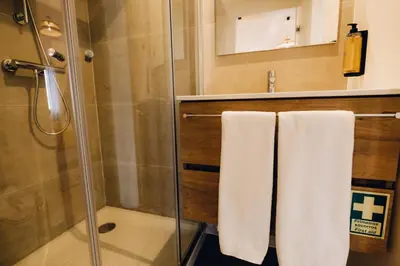 a bathroom with a shower and two white towels at Casas do Calhau Miúdo - Seixal in Seixal
