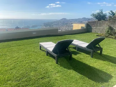 two chairs sitting on top of a field of grass at Myrtus - House with sea view and garden in Funchal