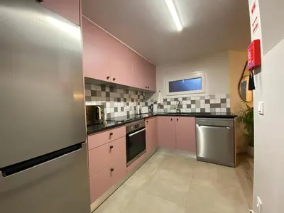 a kitchen with pink cabinets and a stainless steel refrigerator at Myrtus - House with sea view and garden in Funchal