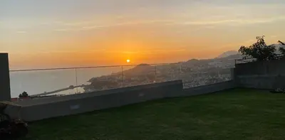 a view of the sunset from the balcony of a house at Myrtus - House with sea view and garden in Funchal
