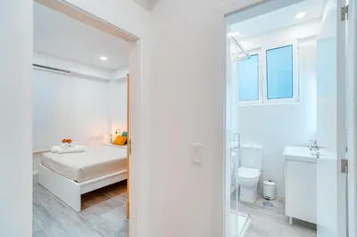 a white bedroom with a bed and a bathroom at Os Fragosinhos II by Amazing Madeira in Funchal
