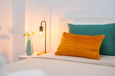 a bed with a orange pillow and a vase of flowers at Os Fragosinhos II by Amazing Madeira in Funchal