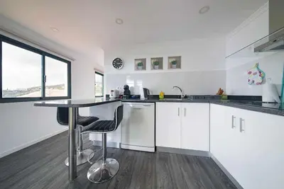 a kitchen with white cabinets and a table with chairs at Lombo do Doutor Cottage 1 by Mth in Calheta