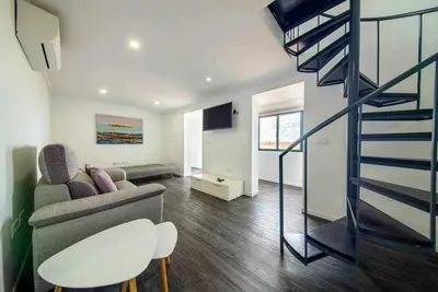 a living room with a couch and a spiral staircase at Lombo do Doutor Cottage 1 by Mth in Calheta