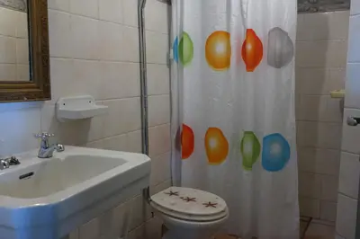 a bathroom with a shower curtain with a toilet and a sink at Chalet Tropical in Arco da Calheta