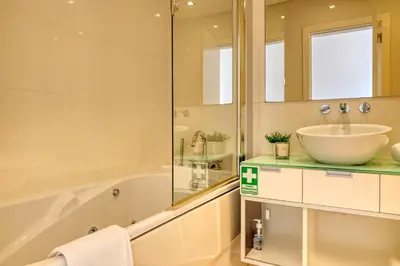 a bathroom with a tub and a sink and a mirror at Jasmineiro, a Home in Madeira in Funchal