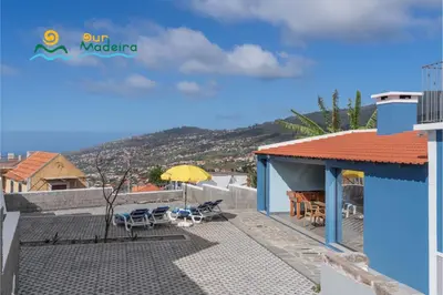 a house with a patio with chairs and an umbrella at Calheta beautiful character cottage Villa Loreto in Arco da Calheta