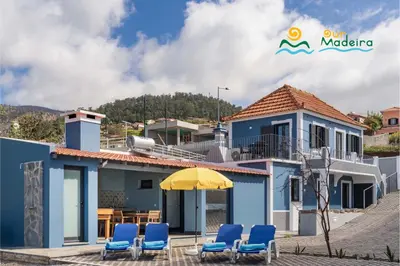 a blue house with blue chairs and an umbrella at Calheta beautiful character cottage Villa Loreto in Arco da Calheta
