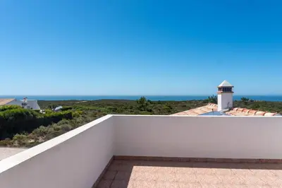 a white balcony with a view of the ocean at Moradia com piscina e vista Mar in Aljezur