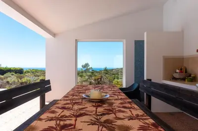 a dining room with a table and a view of the ocean at Moradia com piscina e vista Mar in Aljezur