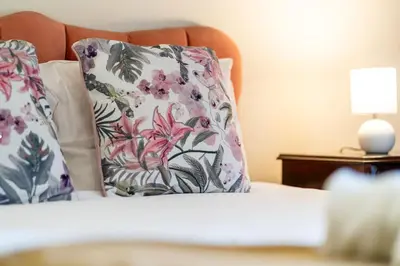 a bed with floral pillows and a lamp on a table at GuestReady - Varanda de belas lembranças in Funchal