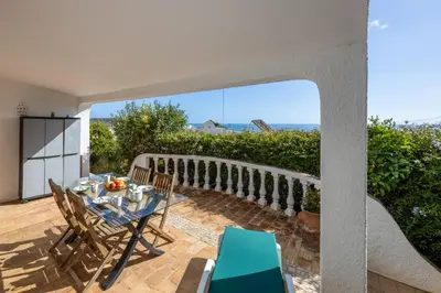 a patio with a table and chairs and a view of the ocean at Casa Coruja in Luz