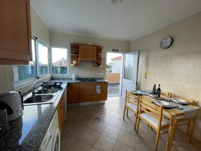 a kitchen with a sink and a table with chairs at Wanderlust House in Ponta Delgada