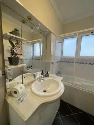 a white bathroom with a sink and a shower at Wanderlust House in Ponta Delgada