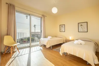a bedroom with two beds and a large window at Villa Angela- Madeira Inn Group in Calheta