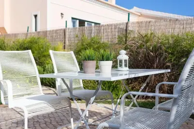 a table with three chairs and a table with plants at Villa T3 com Jardim Vila Sagres M8 in Sagres