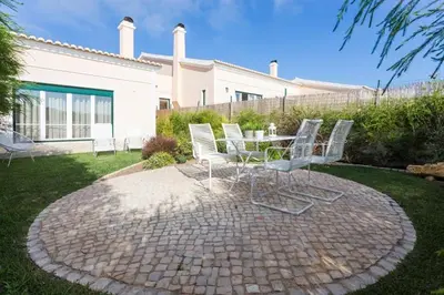 a group of white chairs and a table in a yard at Villa T3 com Jardim Vila Sagres M8 in Sagres