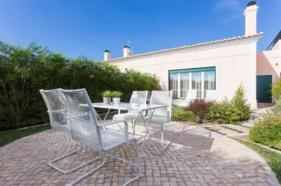 four chairs and a table in front of a house at Villa T3 com Jardim Vila Sagres M8 in Sagres