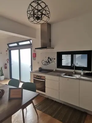 a kitchen with white cabinets and a table and a sink at Mazelia's House in Gaula