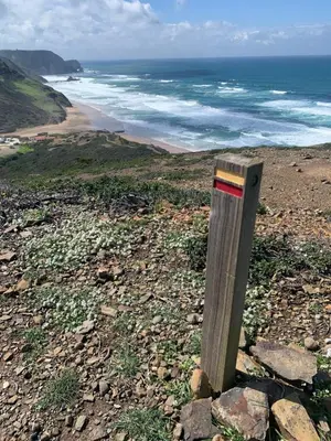 a wooden post on a rocky beach with the ocean at Casa Bellarosa in Raposeira