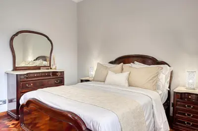 a bedroom with a bed with a dresser and a mirror at Villa Rosa, a Home in Madeira in Funchal