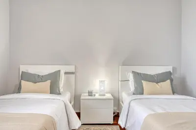 a bedroom with two beds with white sheets and a night stand at Villa Rosa, a Home in Madeira in Funchal