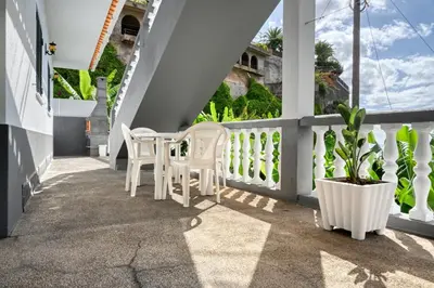 a porch with white chairs and a plant at Villa Rosa, a Home in Madeira in Funchal