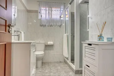 a white bathroom with a toilet and a shower at Villa Rosa, a Home in Madeira in Funchal