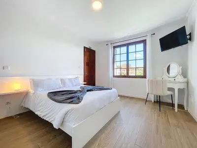 a white bedroom with a bed and a desk and a window at Madeiran Sweet Home in Funchal