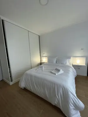 a white bedroom with a large white bed with two lamps at Madeiran Sweet Home in Funchal