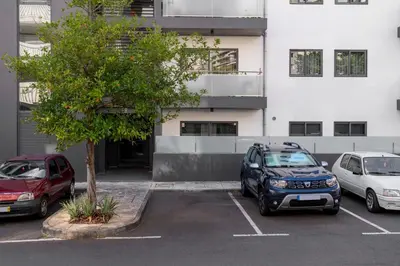 two cars parked in a parking lot in front of a building at Barreiros IV by An Island Apart in Funchal