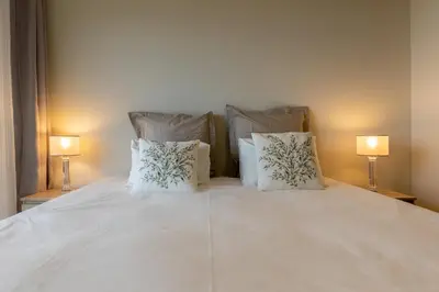 a large white bed with pillows and two lamps at Ocean view and Infinity pool Apartment in Funchal