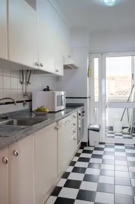 a white kitchen with a black and white checkered floor at GuestReady - Tranquil Nest in Funchal in Funchal