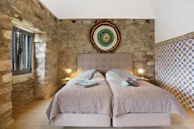 a bedroom with a large bed with a stone wall at Quinta Alcaparras in Porto Santo