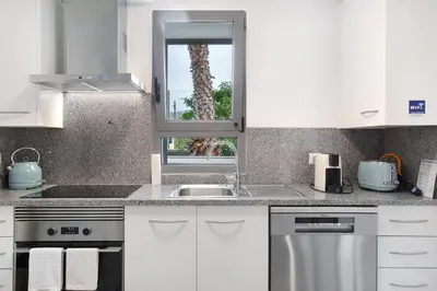 a white kitchen with a sink and a window at Casa De Pedra in Porto Santo