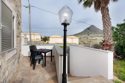 a balcony with a table and a street light at Casa De Pedra in Porto Santo