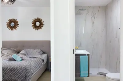 a bedroom with a bed and a bathroom with a mirror at Casa De Pedra in Porto Santo